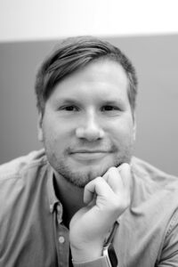 Sort hvitt foto av smilende Alexander Sandtorv