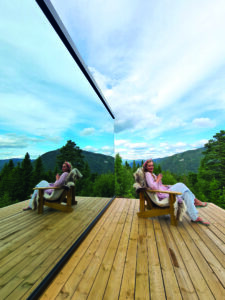 Kvinne som sitter utenfor en hytte i skogen