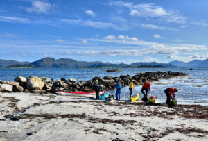 Blå himmel og hav og 4 padlere på stranda