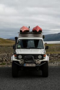 Hvit land rover med 2 røde kajakker på taket